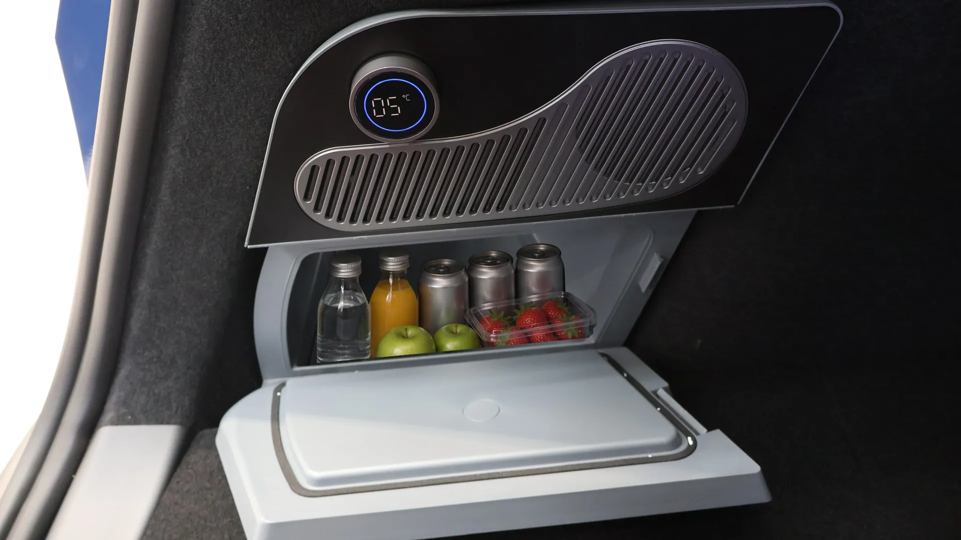 Glacière électrique ouverte vue de face dans le coffre d’une Tesla Model Y, afficheur à 5 °C, bac rempli de boissons
