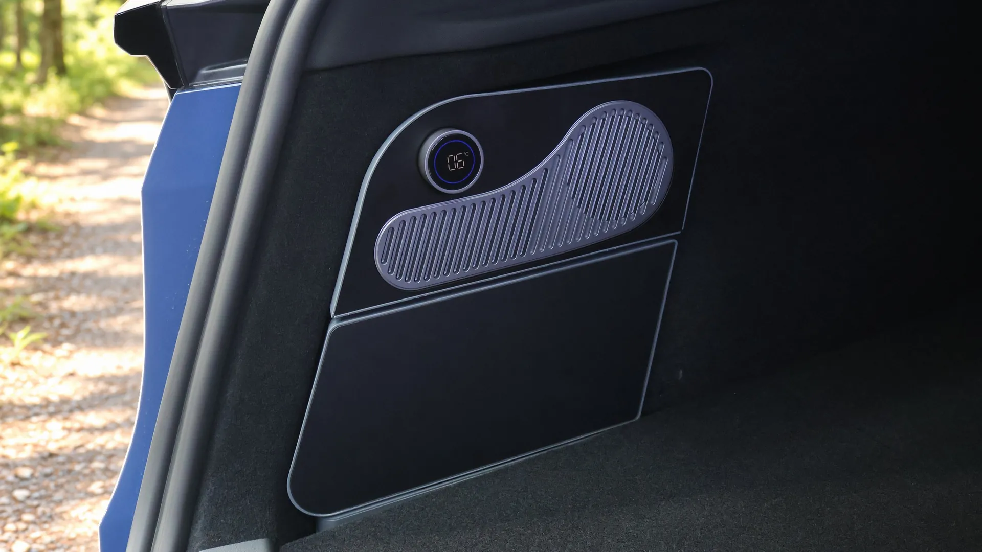 Glacière électrique fermée, façade noire affleurant la garniture gauche du coffre d’une Tesla Model Y