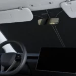 Pare-soleil de pare-brise noir d’une seule pièce posé derrière le pare-brise d’une Tesla Model 3 Highland, vu depuis la place du conducteur