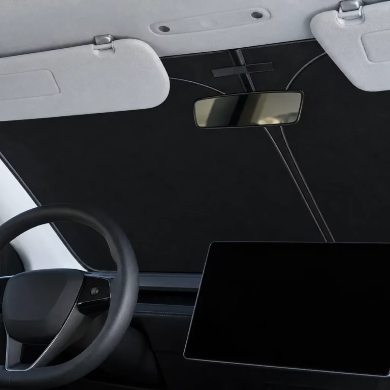 Pare-soleil de pare-brise noir d’une seule pièce posé derrière le pare-brise d’une Tesla Model 3 Highland, vu depuis la place du conducteur