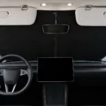 Pare-soleil de pare-brise noir d’une seule pièce posé derrière le pare-brise d’une Tesla Model Y Juniper, pare-soleil de la voiture rabattus, écran central éteint