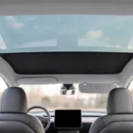 Pose du pare-soleil dans une Tesla Model Y : le panneau avant est en place, la partie arrière du toit vitré laisse encore voir le ciel