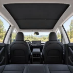 Pare-soleil noir installé sous le toit vitré, vue large de l’habitacle noir de la Tesla Model Y Juniper