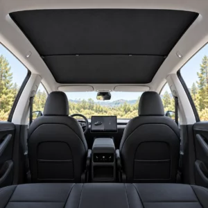 Pare-soleil noir installé sous le toit vitré, vue large de l’habitacle noir de la Tesla Model Y Juniper