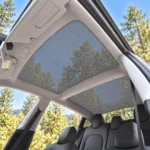 Pare-soleil en maille grise sous le toit vitré de la Tesla Model 3 Highland, vue depuis la portière